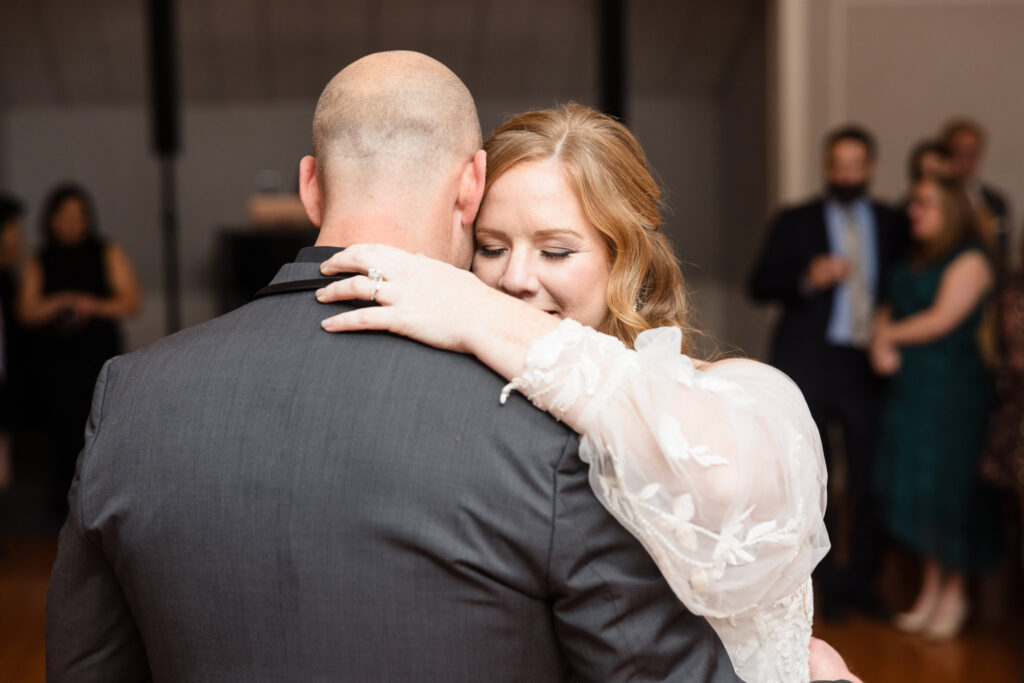 Bride resting her head on groom's shoulder during first dance.