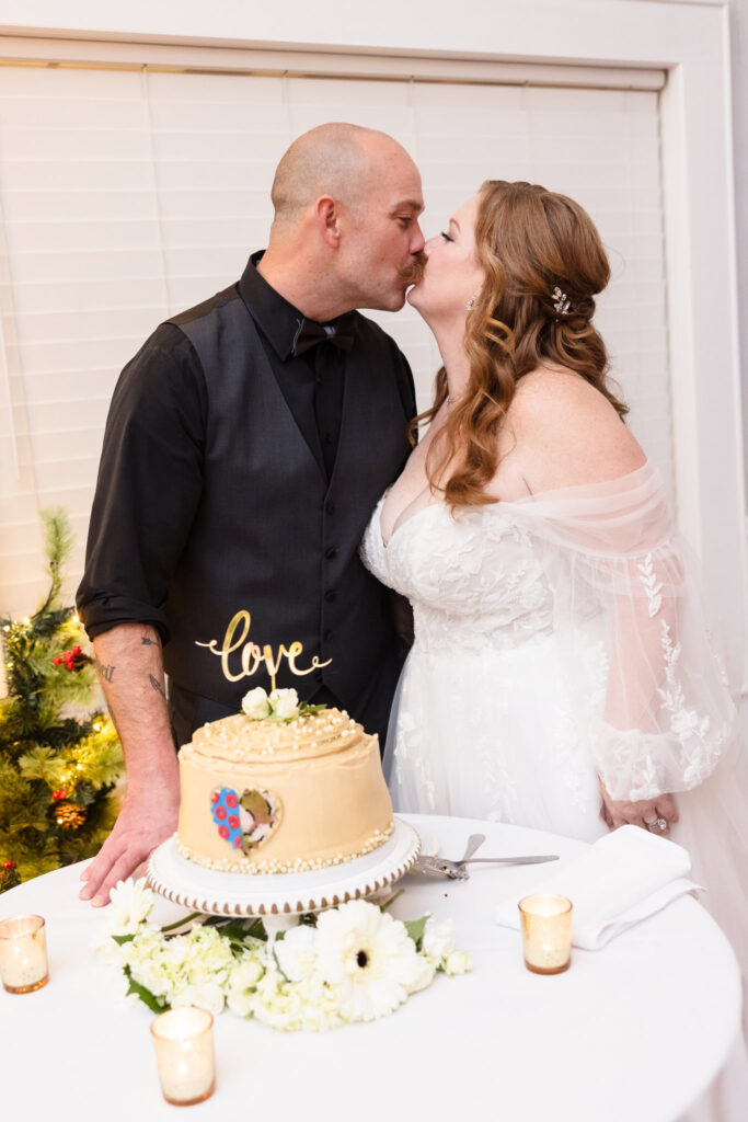 Bride and groom kissing in front of wedding cake.