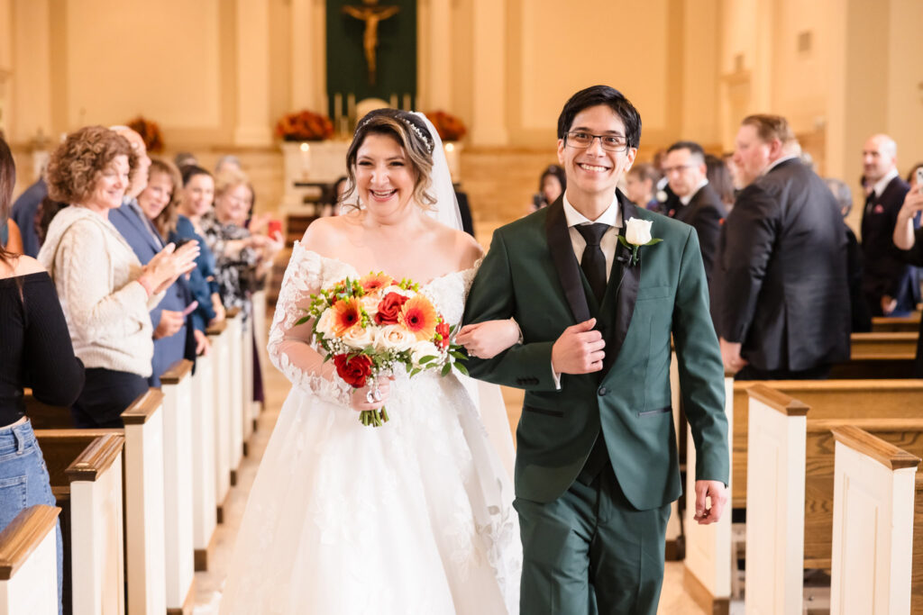 Bride and groom smiling as they walk down the aisle after the ceremony at St. Philip Neri in Northport. 