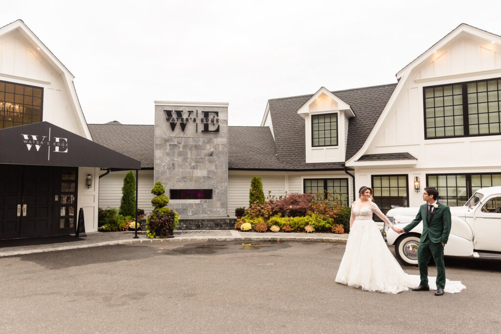 Bride and groom holding hands as they walk across the front of Water's Edge in Centerport.