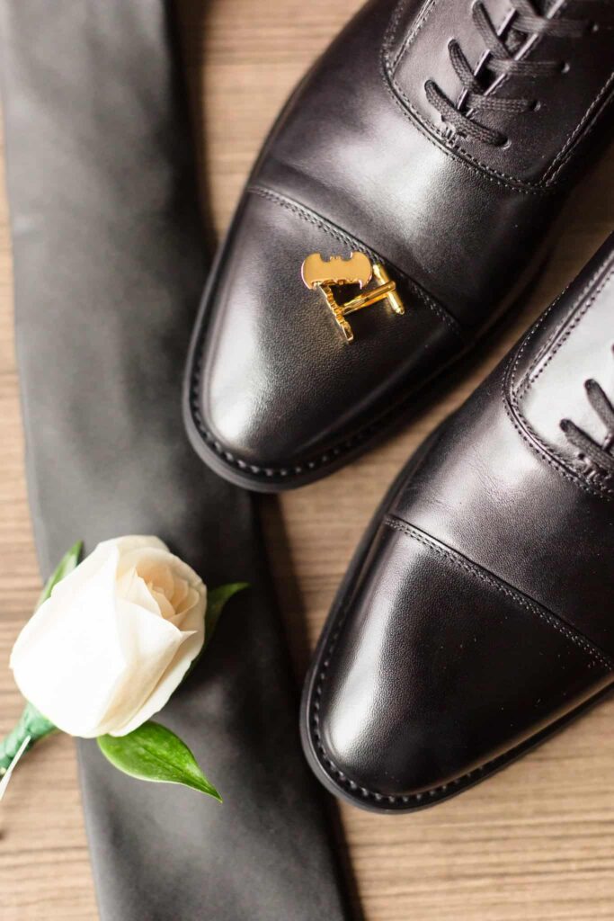 Groom's shoes, cufflinks, flower, and tie.