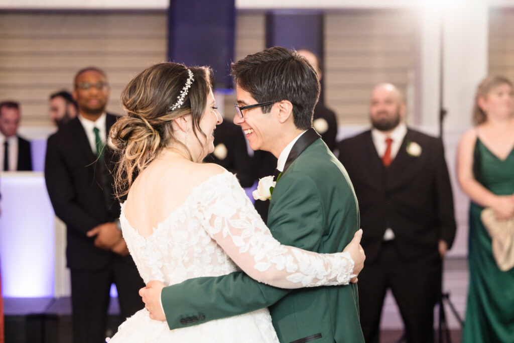 Bride and groom smiling at each other while they dance. 