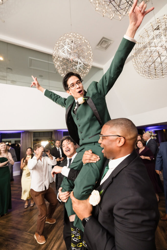 Groom is being lifted up. He has his hands over his head. 