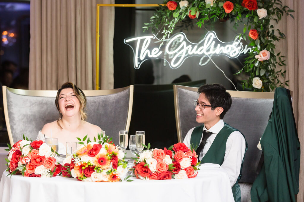 Bride and groom laughing while they listen to toasts.