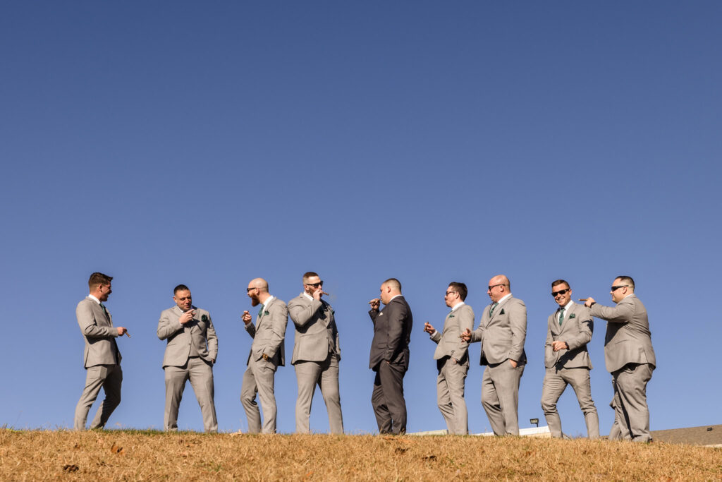 Groomsmen at the top of a hill smoking cigars at the Stonebridge Country Club.