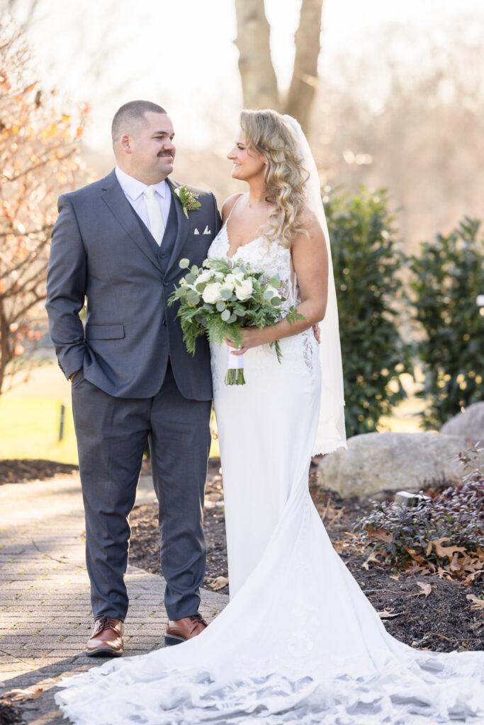 Full length image of bride and groom smiling at each other. 