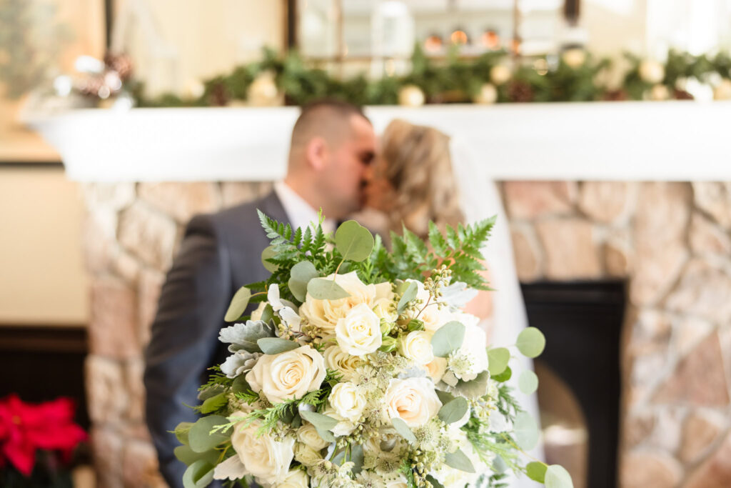 Bride and groom kissing with the bride's bouquet in focus. 