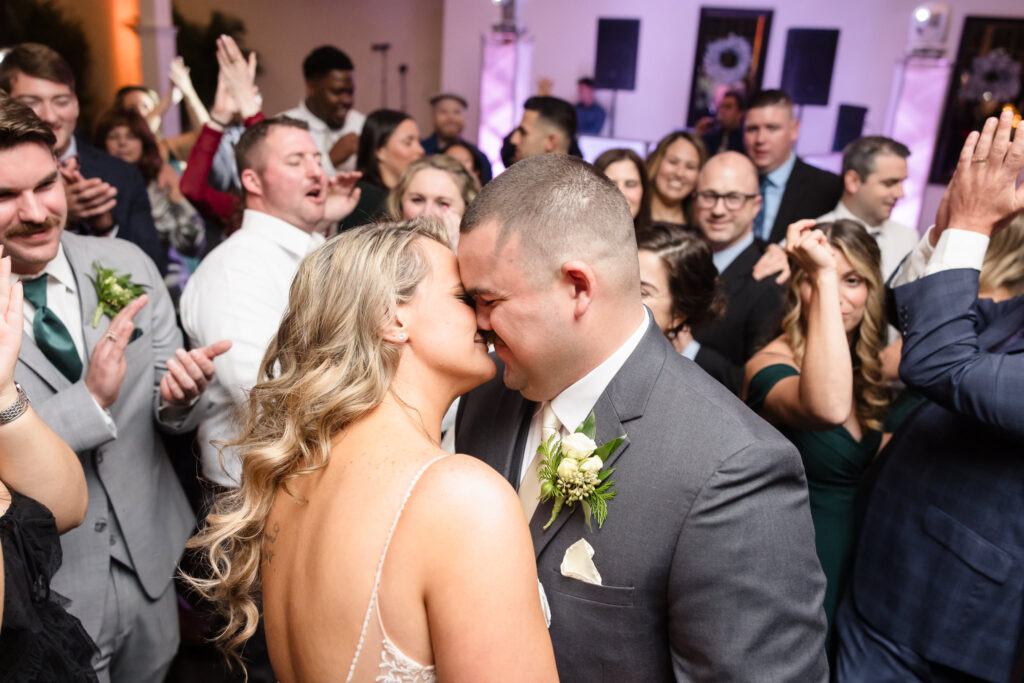 Bride and groom kissing surrounded by their guests. 