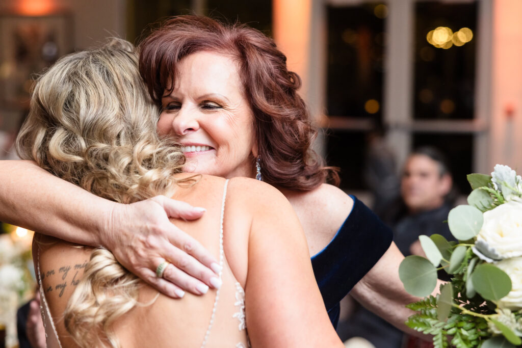 Mother of the bride smiling while she hugs the bride.