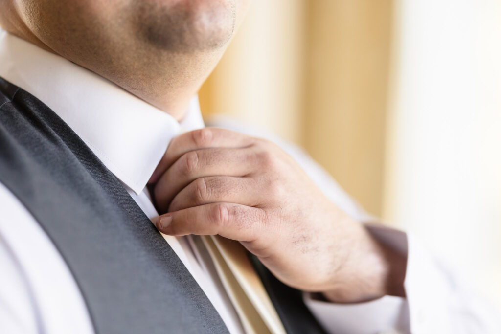 Groom adjusting his tie in the grooms suite.