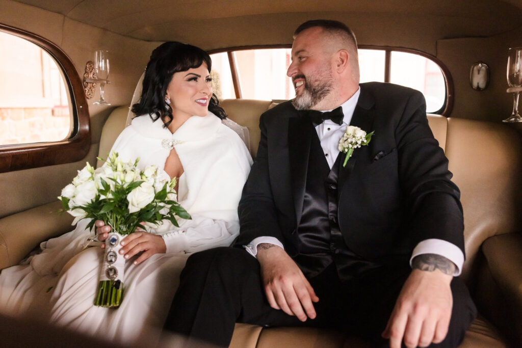 Bride and groom in Rolls Royce smiling at each other at Inn at New Hyde Park.