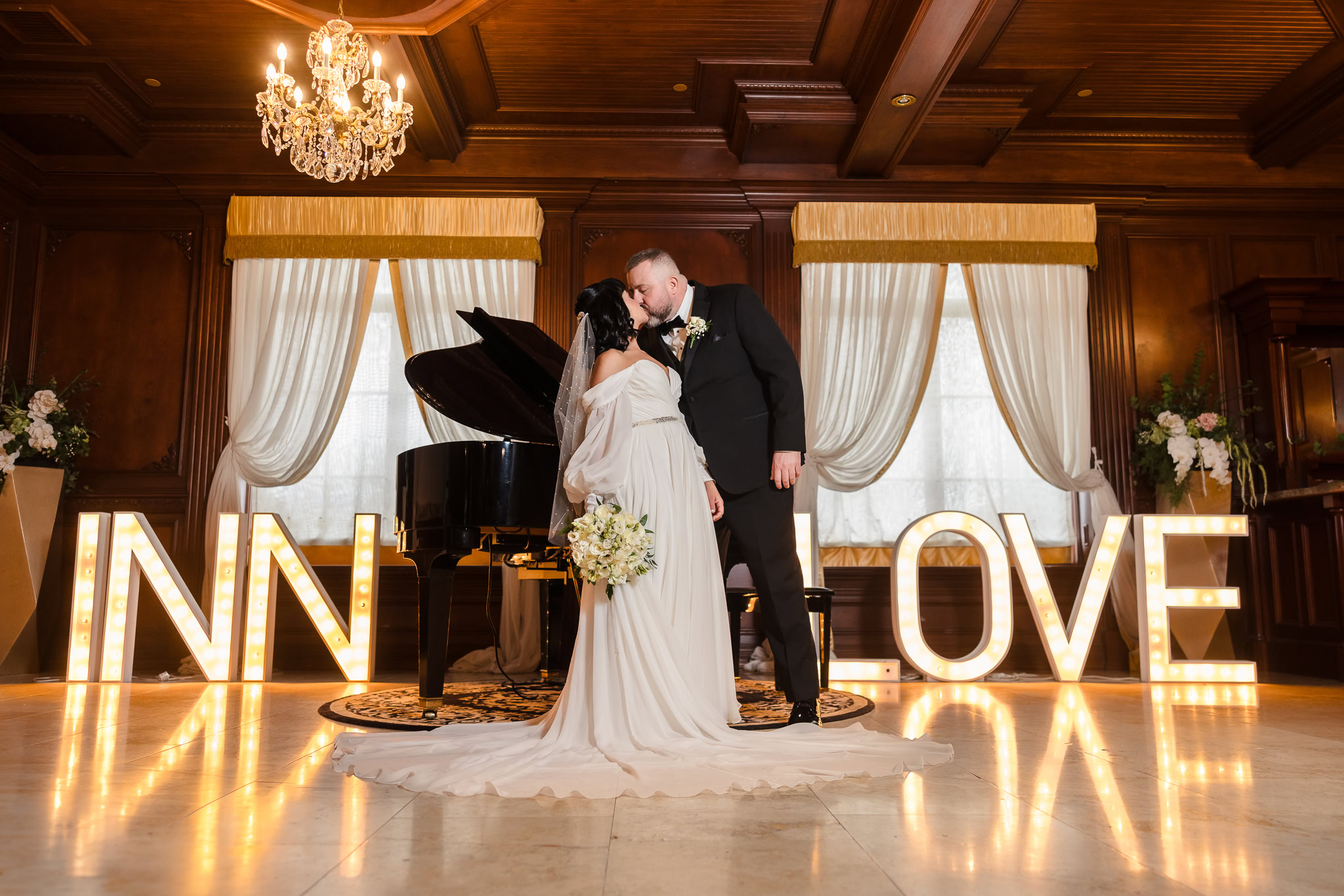 Couple in lobby of Inn at New Hyde Park kissing in front of Inn Love sign