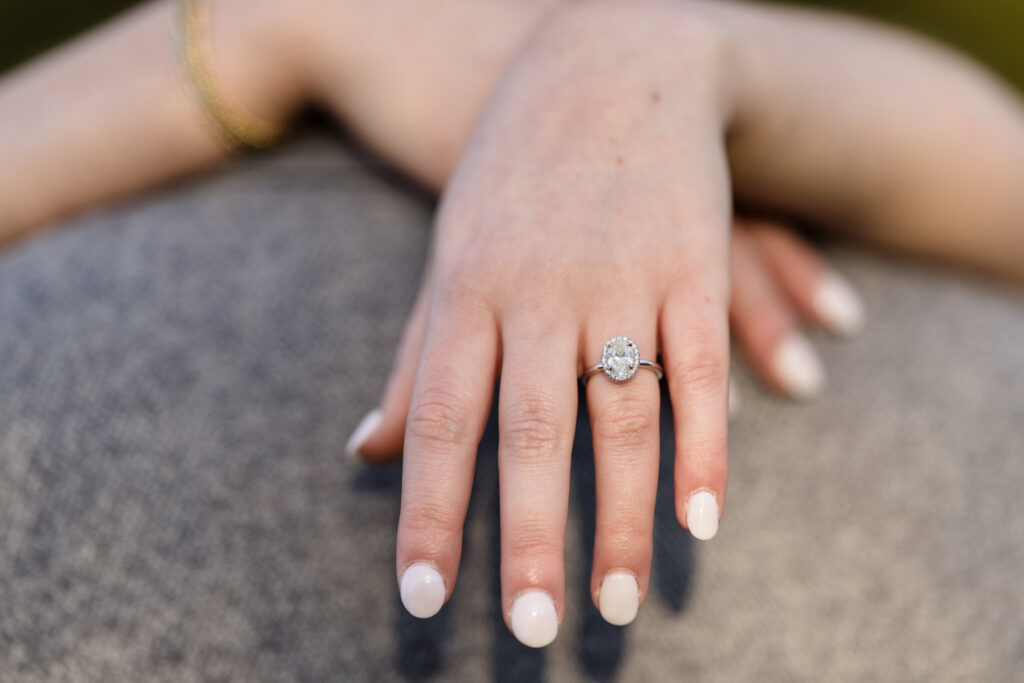 Close-up of engagement ring as bride rests her hand gently on his shoulder.