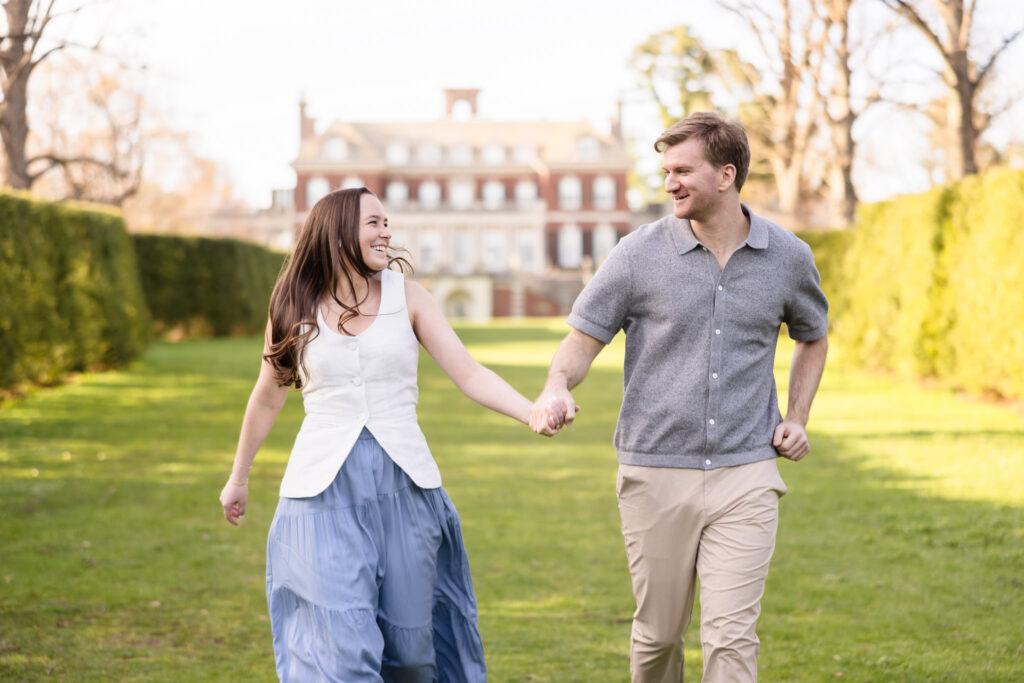 Couple running joyfully in front of the mansion.