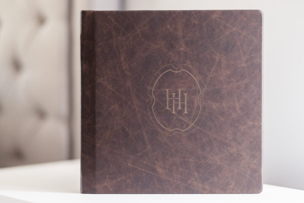 Close-up of a handcrafted leather wedding album featuring the Heritage House monogram, symbolizing timeless legacy and luxury photography.