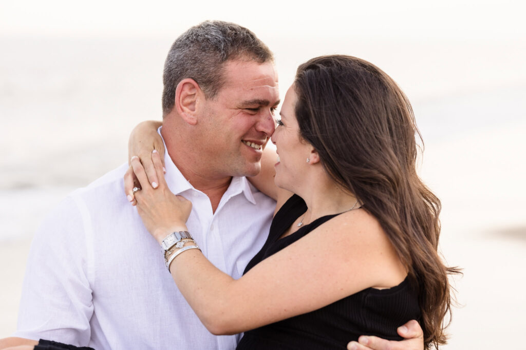 Close-up of engaged couple smiling and holding each other on the beach at Breezy Point