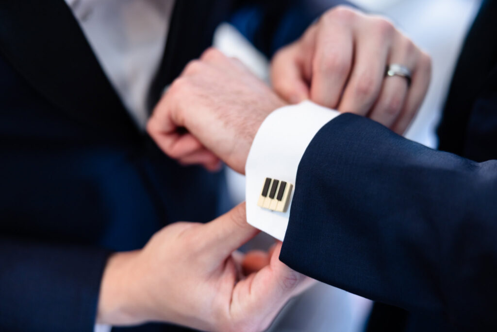 Close-up of a groom fastening gold cufflinks on his shirt sleeve before the wedding at The Briarcliff Manor.