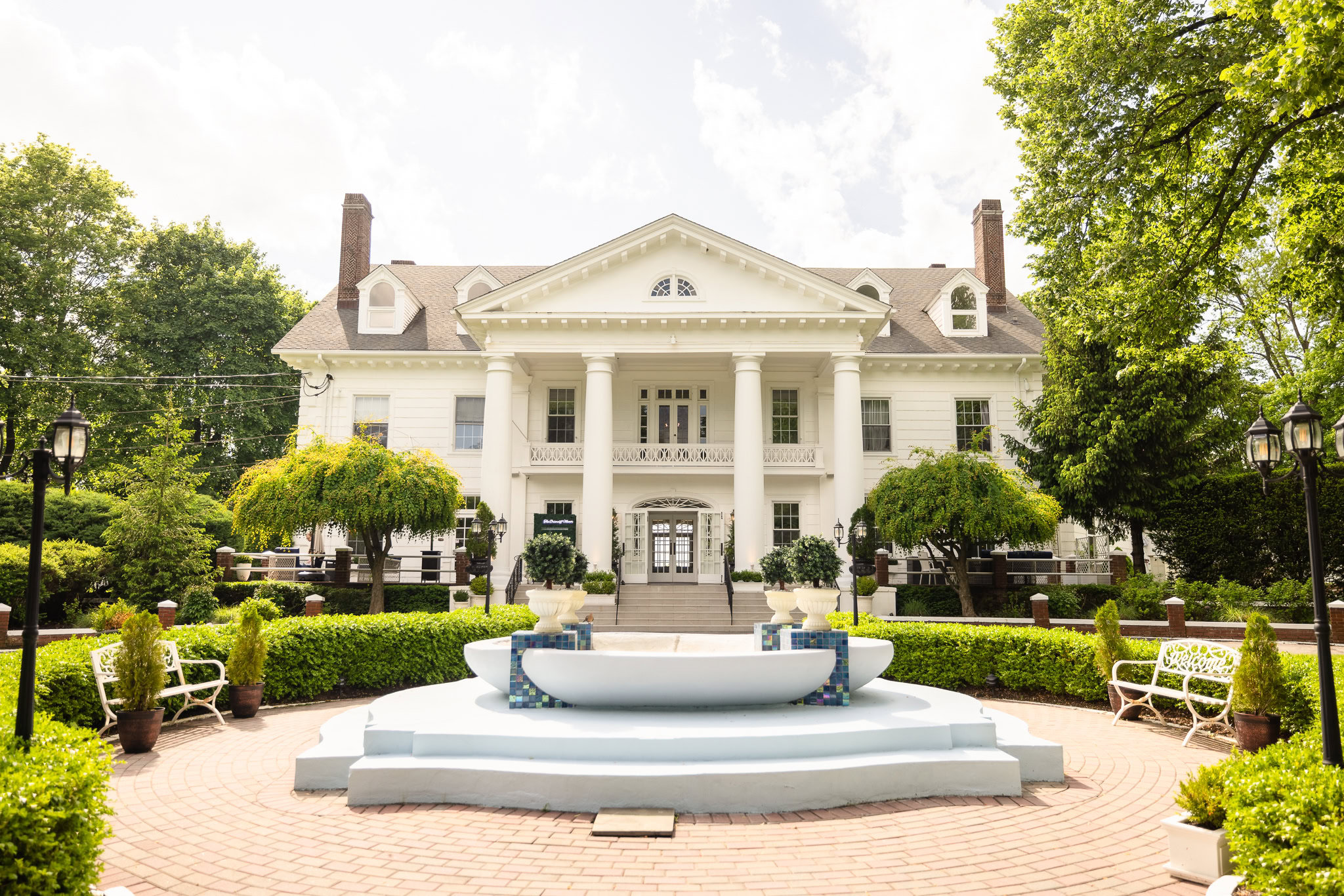 The Briarcliff Manor wedding venue with grand white columns, manicured gardens, and a central fountain in Westchester, NY.