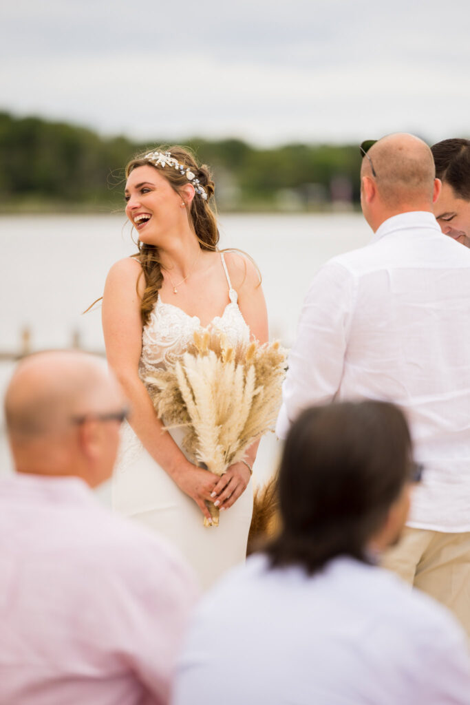 Bride laughing during the ceremony, holding a bouquet of pampas grass.
