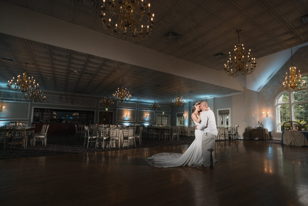 Bride and groom share a private dance in a chandelier-lit ballroom with romantic ambiance.