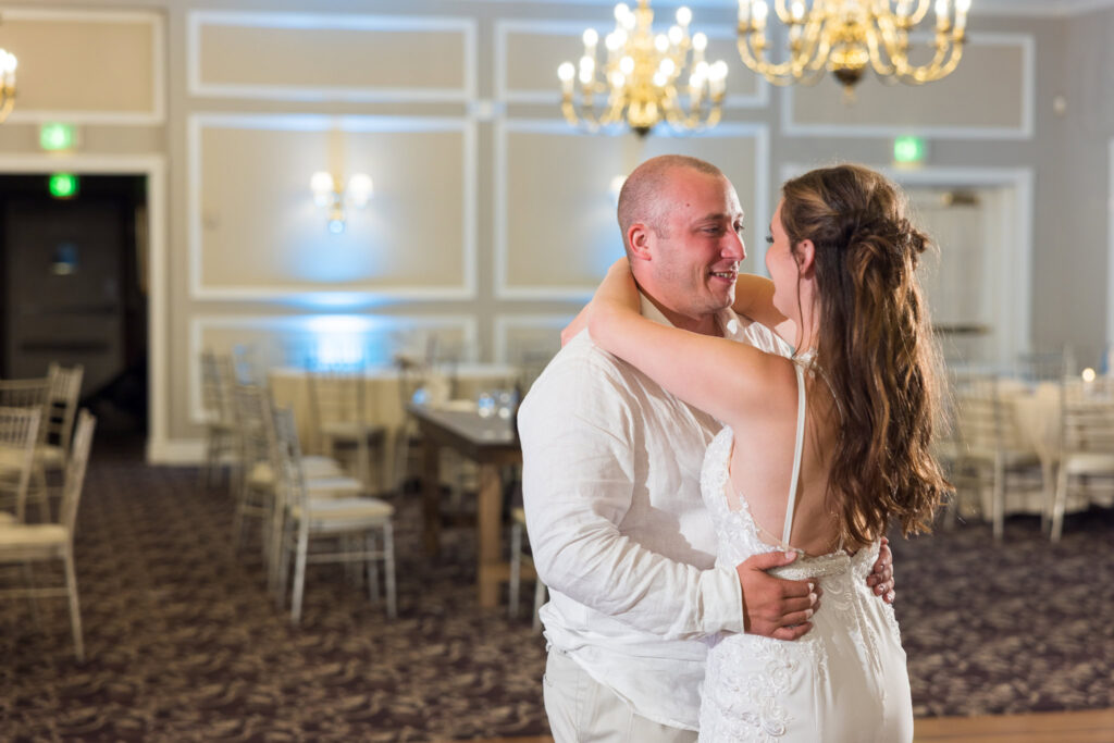 Bride and groom dancing together in a warmly lit reception room.
Bride and groom dancing together in a warmly lit reception room.