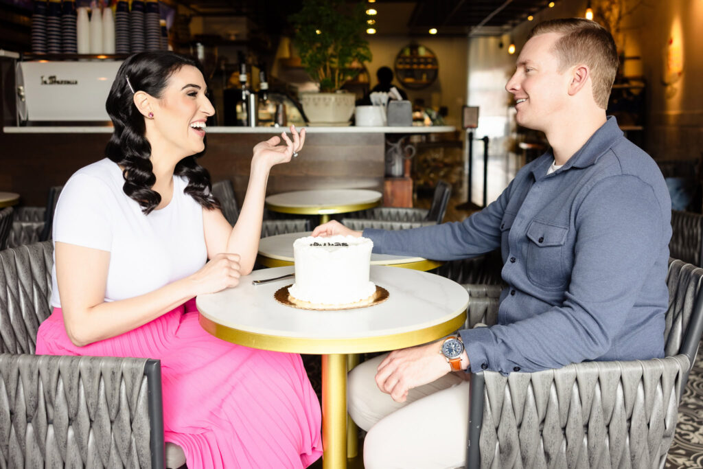 Engaged couple Christine and Bill sharing laughter over cake at Sugarberry café in Rockville Centre during their sentimental engagement session