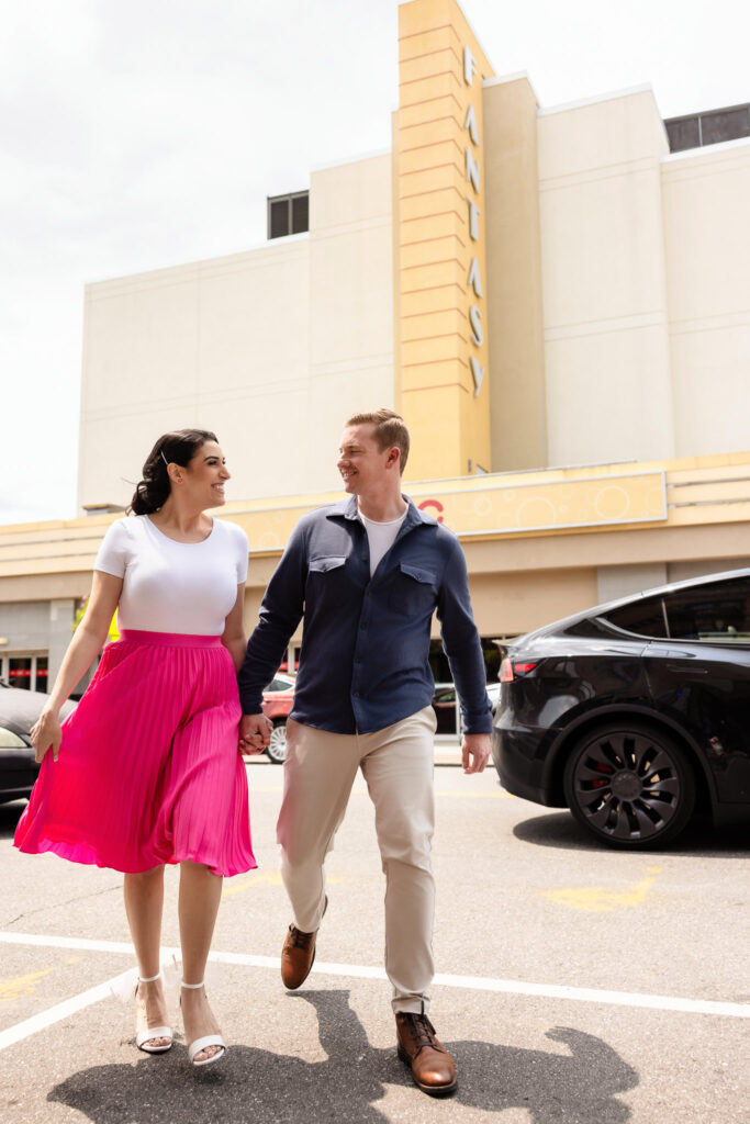 Engaged couple Christine and Bill holding hands and walking in front of the iconic Fantasy Theatre in Rockville Centre during their engagement session