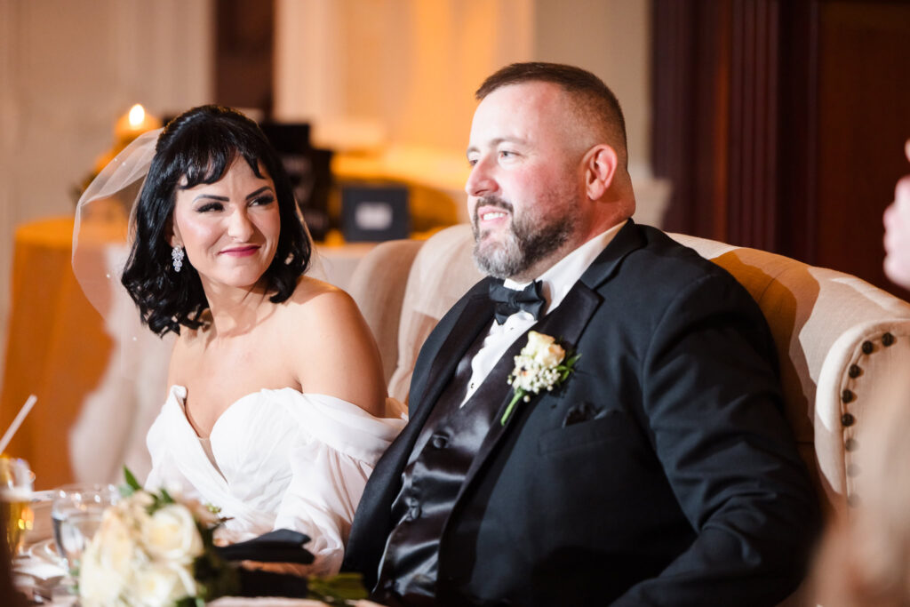 Bride and groom seated together during their wedding reception at The Inn at New Hyde Park, sharing a joyful and heartfelt moment under soft candlelight.

