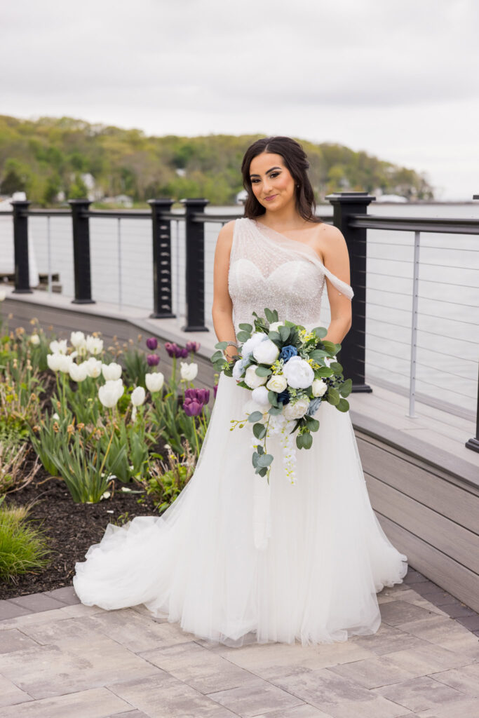 Bride poses in her wedding gown by the waterfront garden at Water’s Edge Centerport.