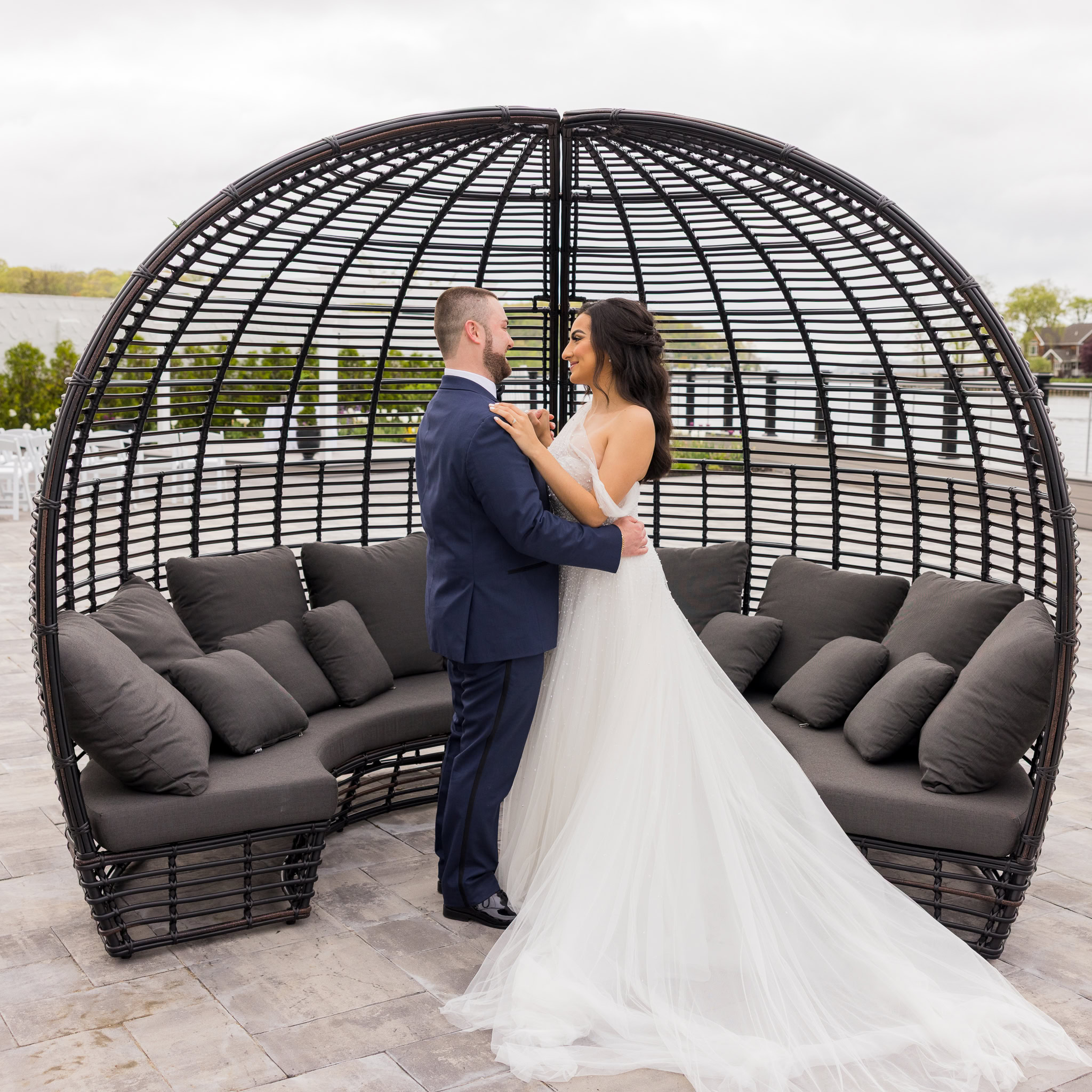 Bride and groom share a quiet moment inside a black lounge pod on the terrace at Water’s Edge Centerport.