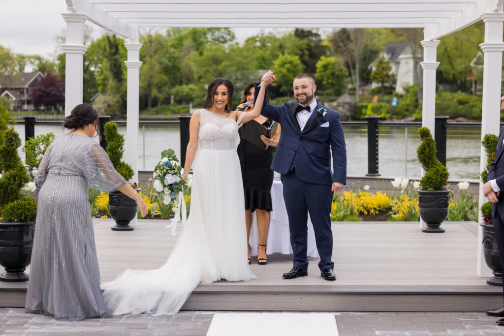Bride and groom celebrate just after their outdoor ceremony under the white pergola at Water’s Edge Centerport.
