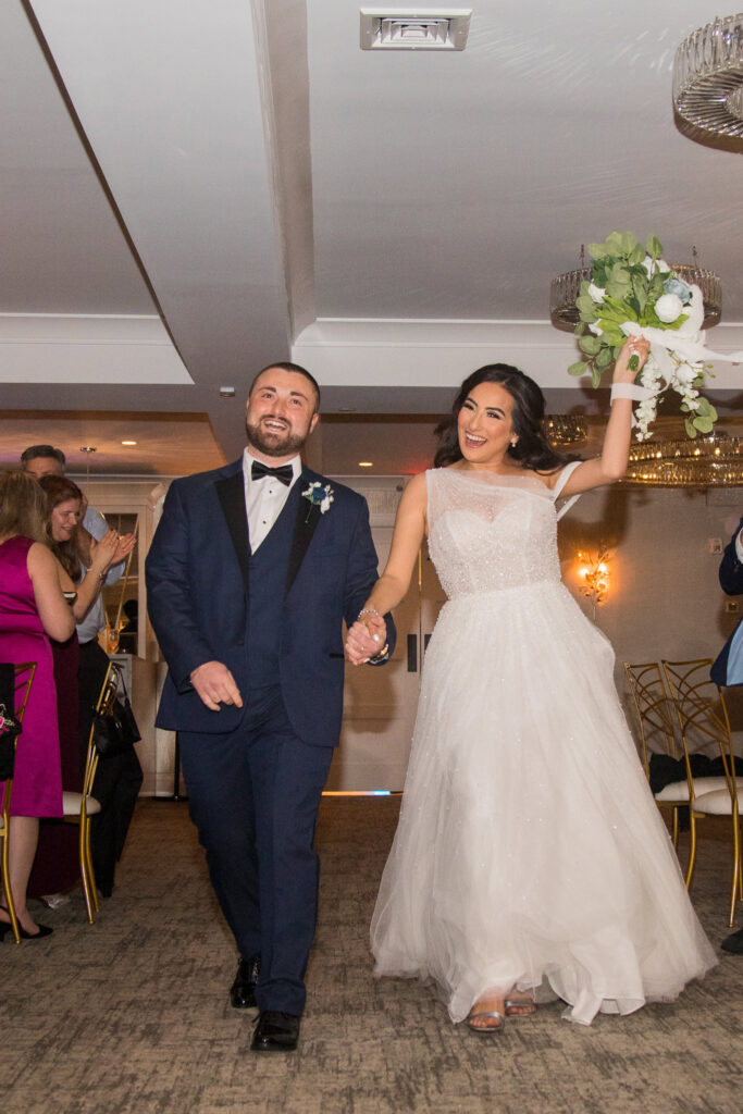Bride and groom make their grand entrance into the reception smiling and celebrating at Water’s Edge Centerport.