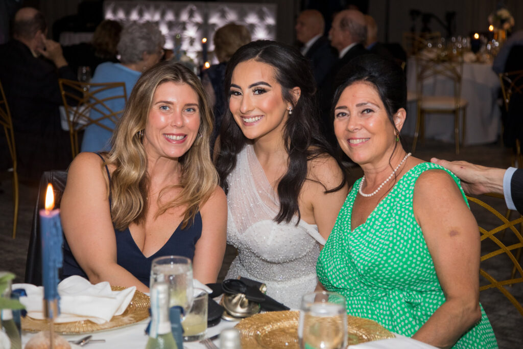 Bride poses for a photo with guests during the wedding reception at Water’s Edge Centerport.