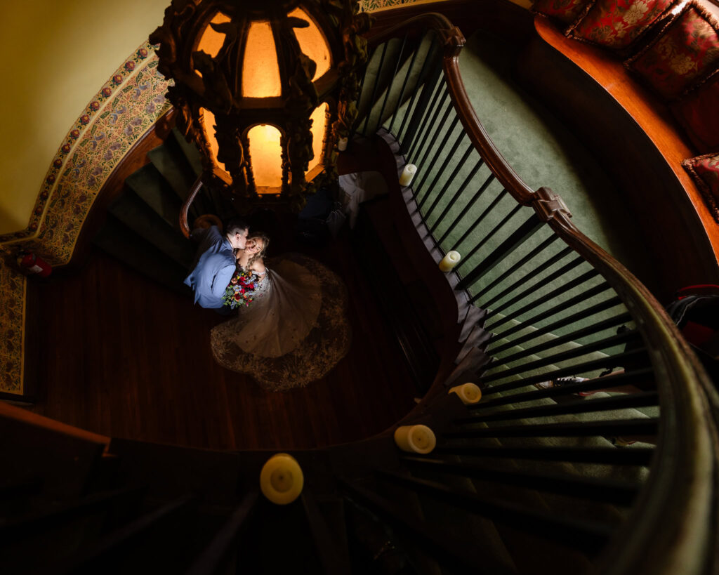 Overhead view of couple framed by spiral staircase and golden chandelier