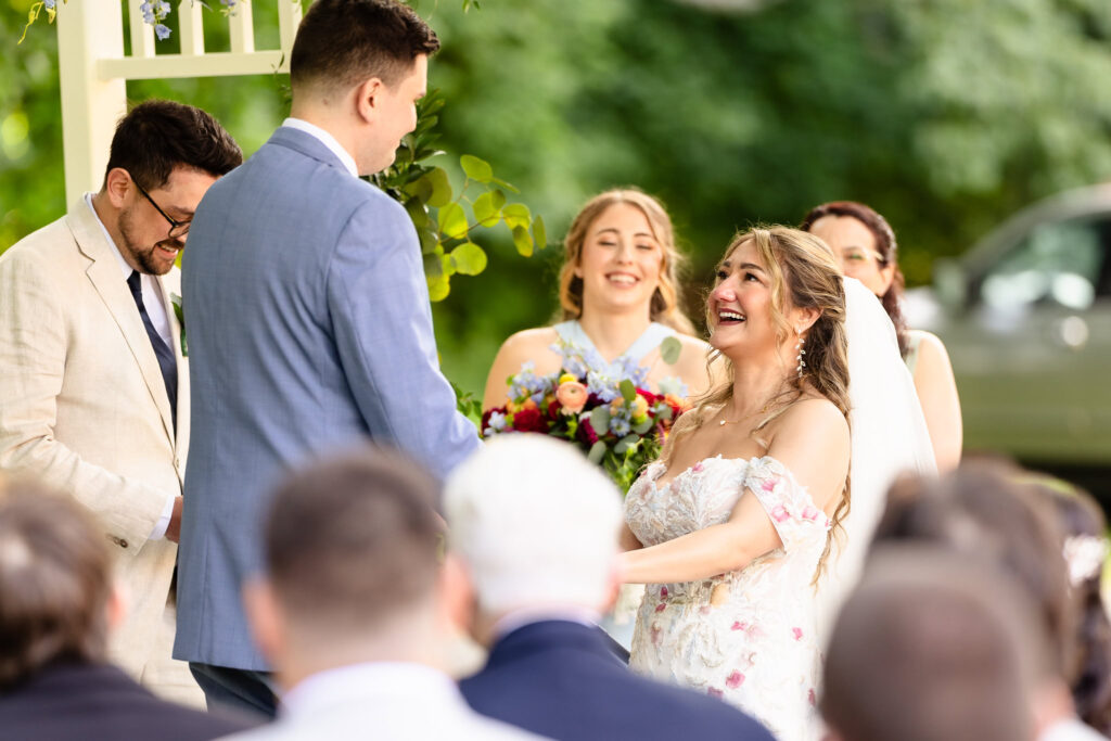 Bride and groom exchanging vows under soft light and surrounded by loved ones