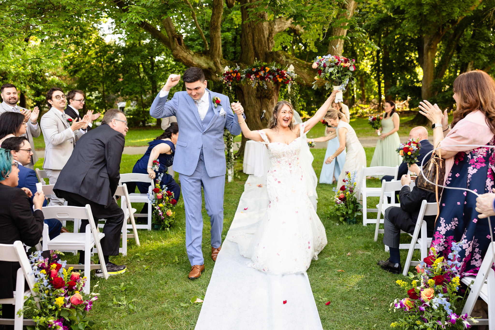 Bride and groom walk joyfully down the aisle as guests cheer and celebrate