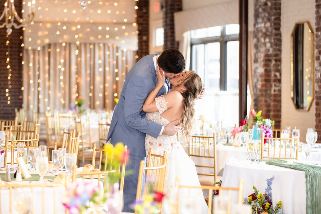 Romantic reception kiss captured during candlelit dinner celebration