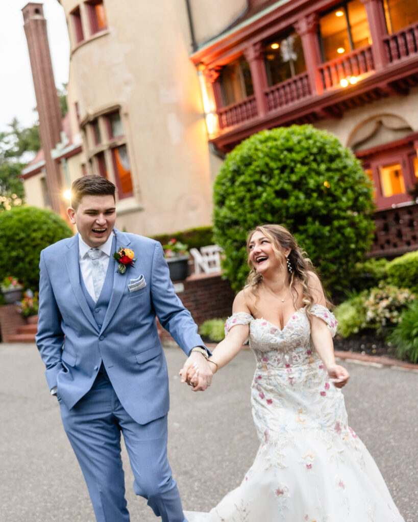 Bride and groom laughing while walking outside historic estate