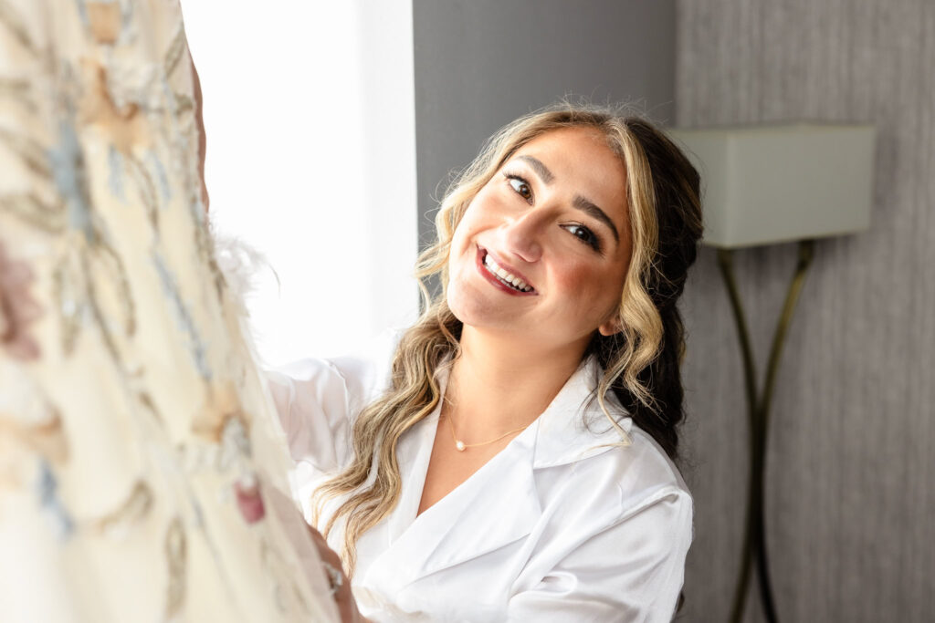 Bride smiling as she sees her gown, filled with calm and joy on wedding morning