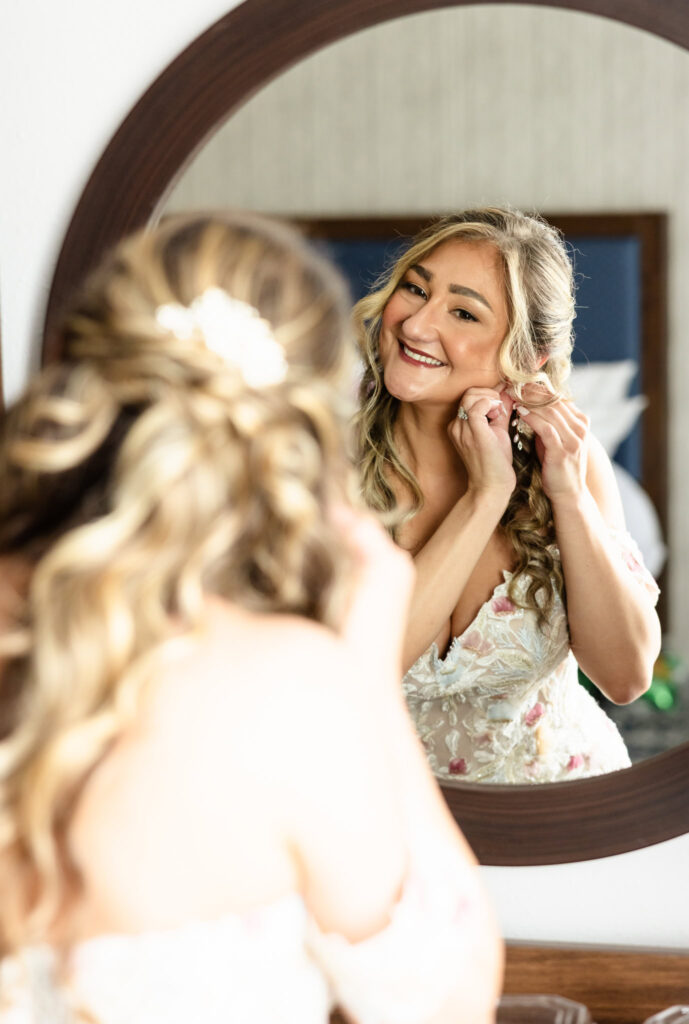 Bride placing earring with soft expression, reflected in mirror before Coindre Hall ceremony