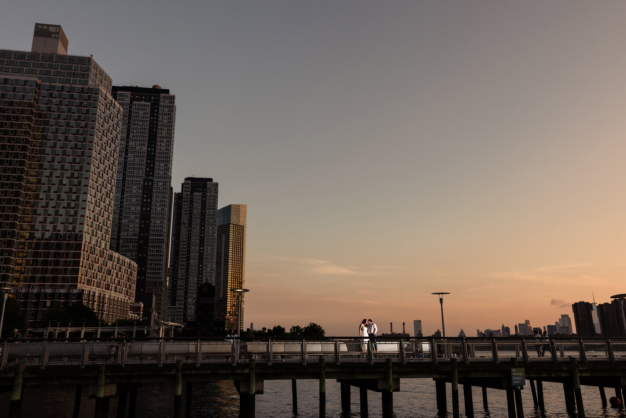 View of the Manhattan skyline at sunset from Gantry Plaza, with warm tones reflecting on the East River.