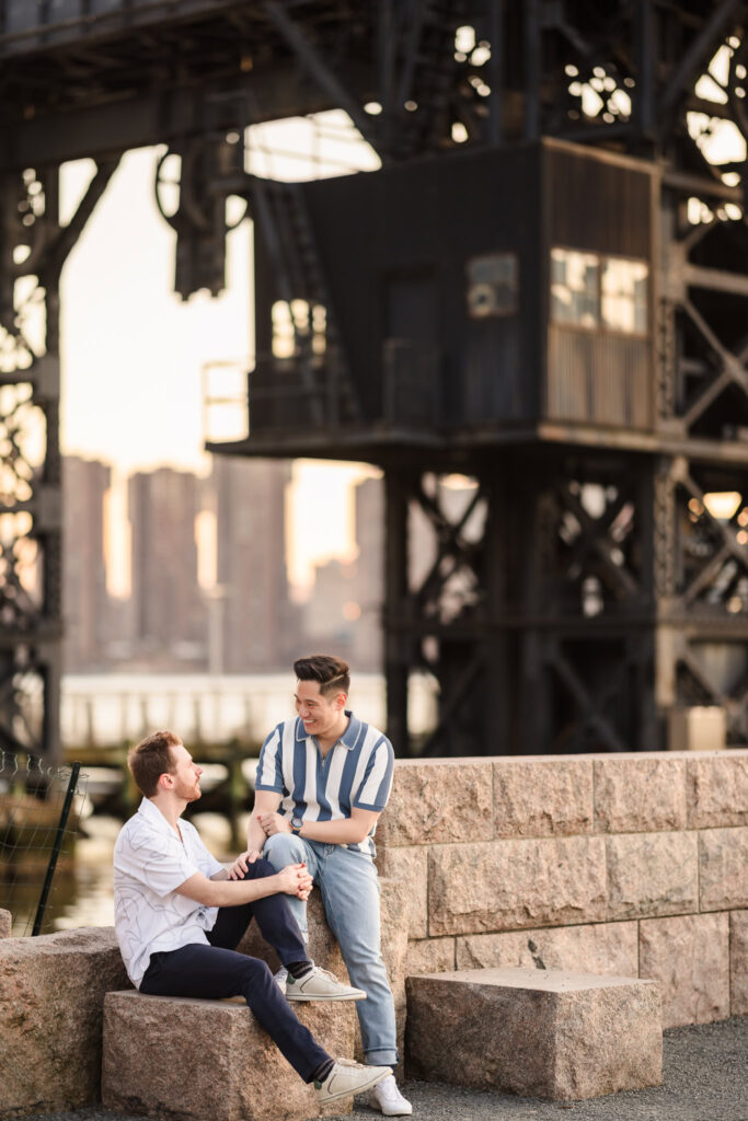 The couple chats naturally while seated on stone steps under the historic gantries, surrounded by industrial textures and urban charm.