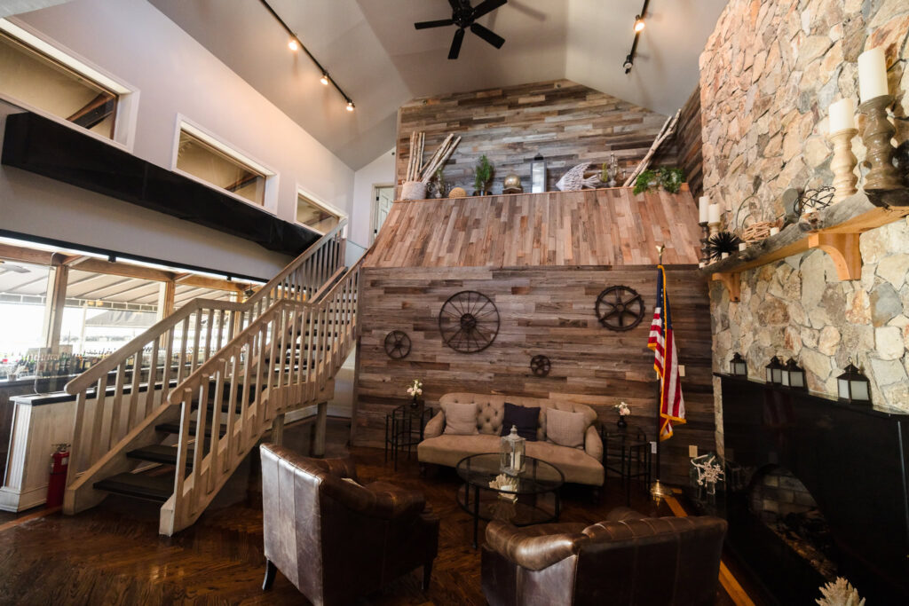Interior lounge space at Land’s End featuring rustic wood paneling, leather seating, a stone fireplace, and nautical-inspired decor.