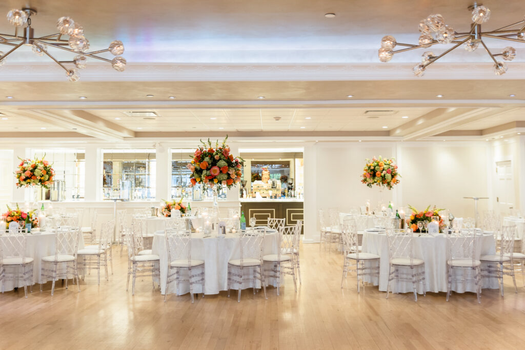 Elegant wedding reception setup inside the Grand Ballroom at Watermill Caterers in Smithtown, featuring floral centerpieces, crystal chairs, and hardwood floors.