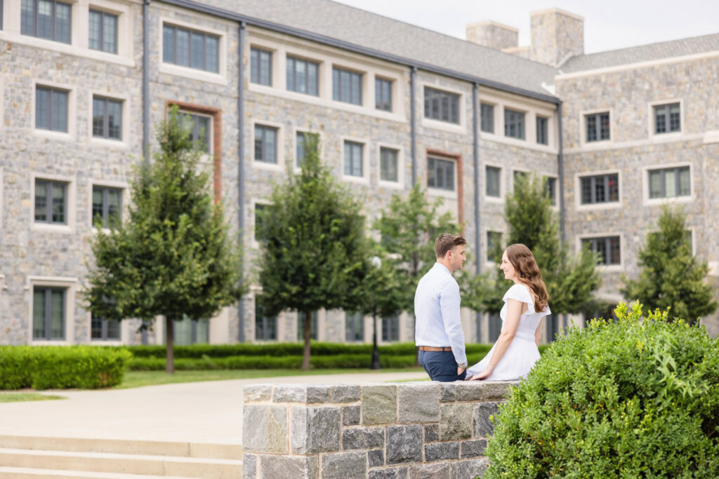 Couple sitting and smiling outside modern campus buildings