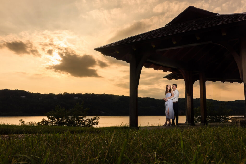 Couple standing under a rustic pavilion at sunset