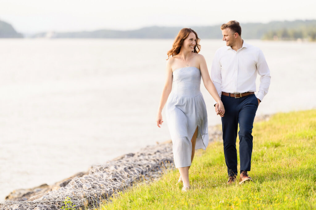 Couple walking barefoot on river path at dusk