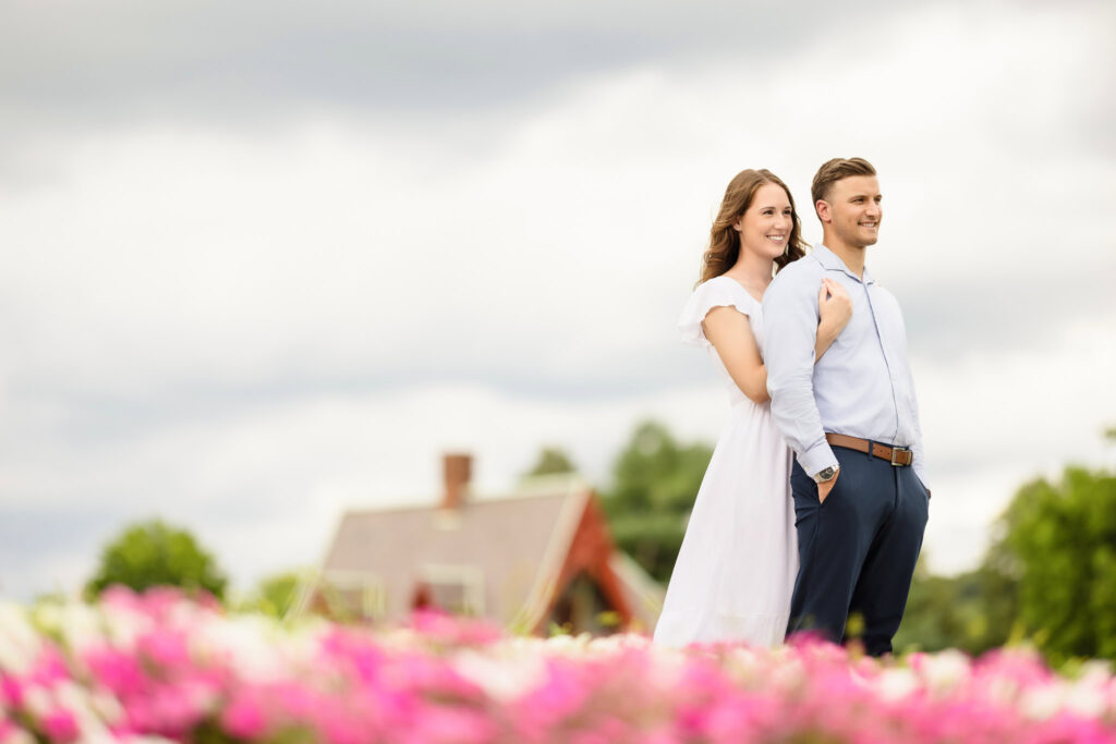 Couple standing close with Hudson Valley rooftops and flowers behind