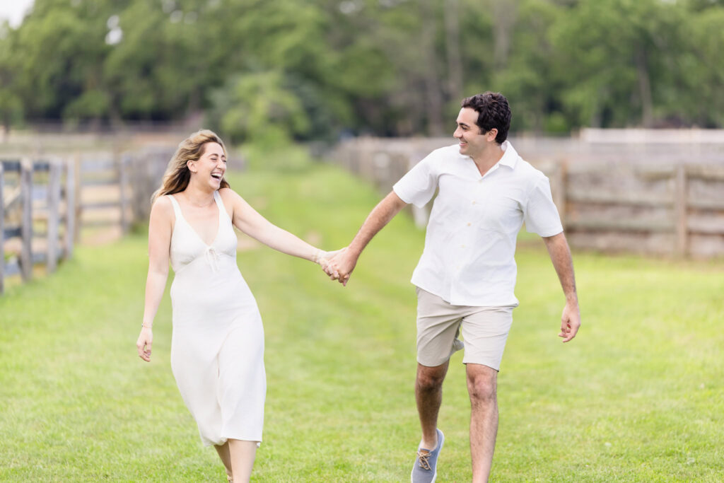 Kristen and James running hand in hand through a wide-open pasture.