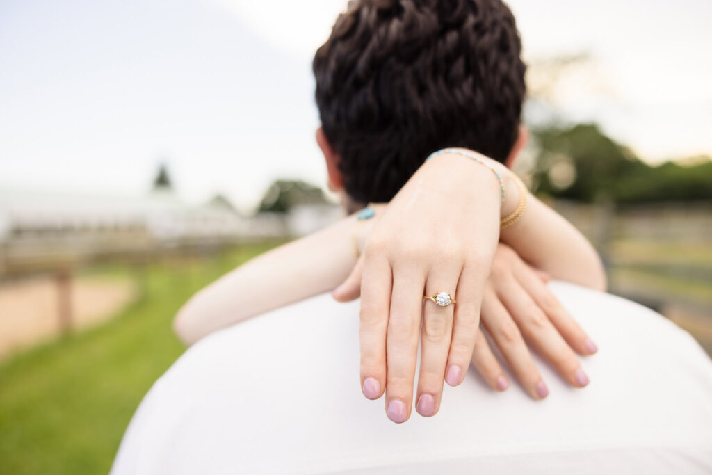 Close-up of Kristen’s hands wrapped around James, showing her ring and gentle affection.
